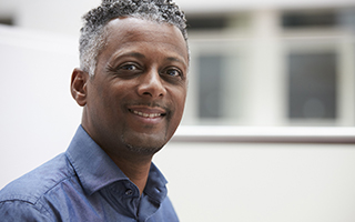 Man with with grey hair and a blue shirt smiling