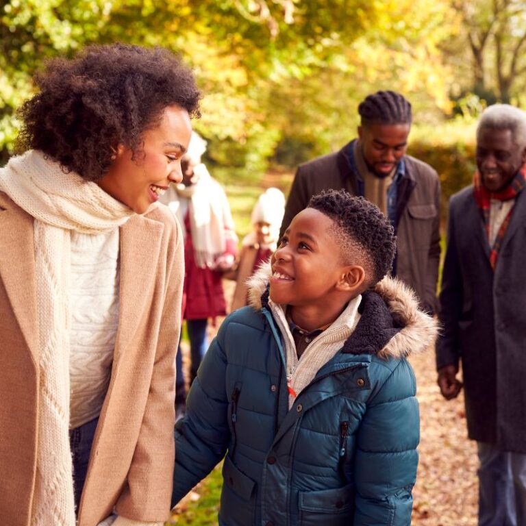 Woman with young boy walking in the park, a man and an older man are walking behind and smiling.