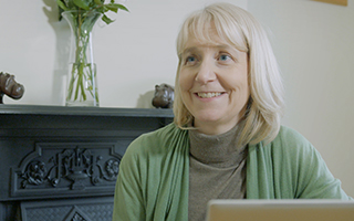 woman with blonde hair and a green cardigan smiling