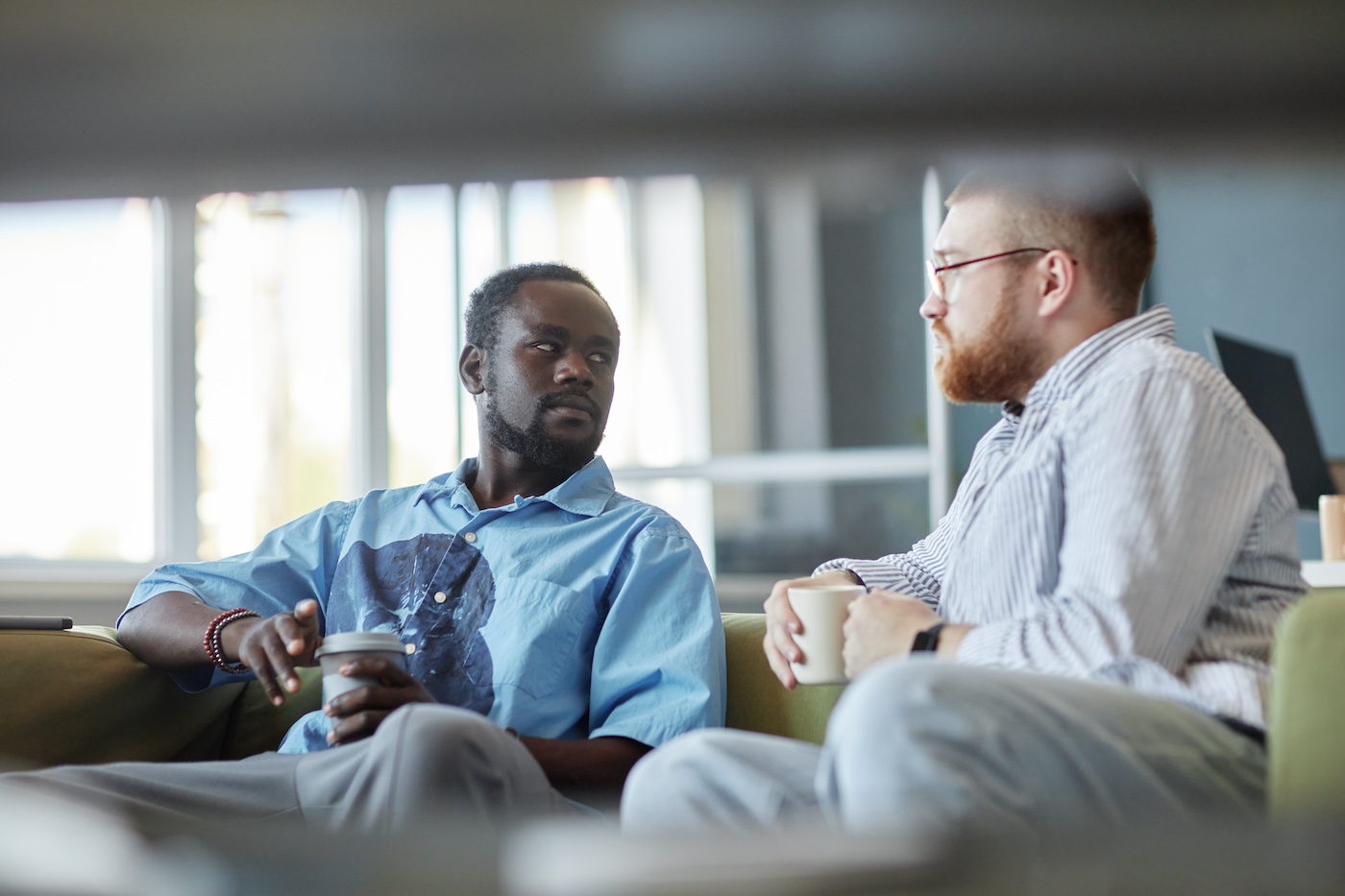 Informal discussion between two people holding coffee cups