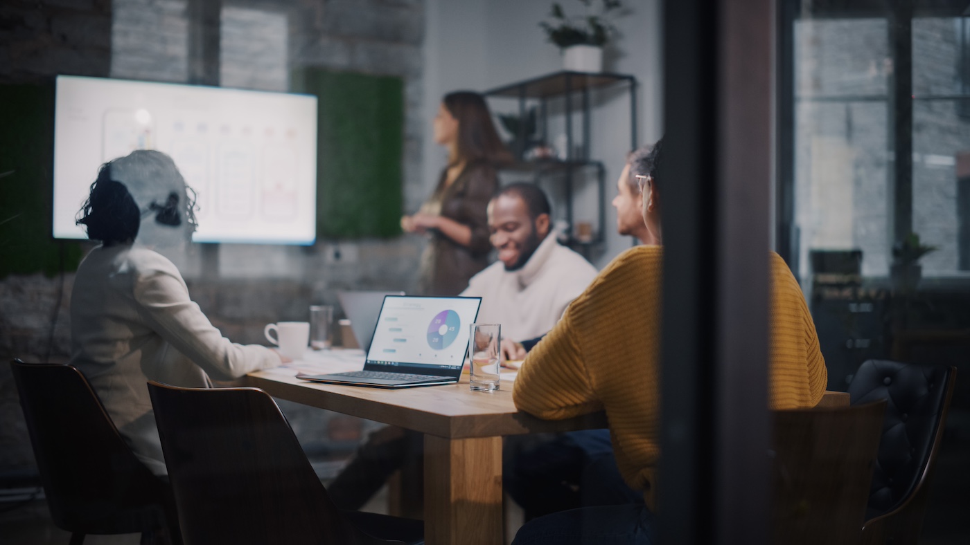 Person presenting to a group around a conference table
