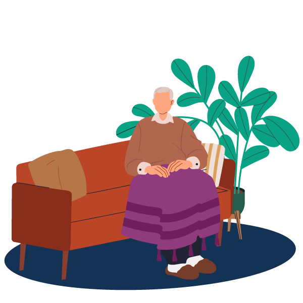 Elderly man sitting on a sofa on his own with a blanket covering his legs.