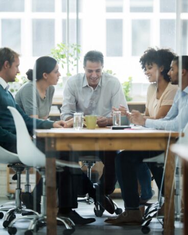 Colleagues enjoying a light-hearted moment during a meeting in a glass-fronted office
