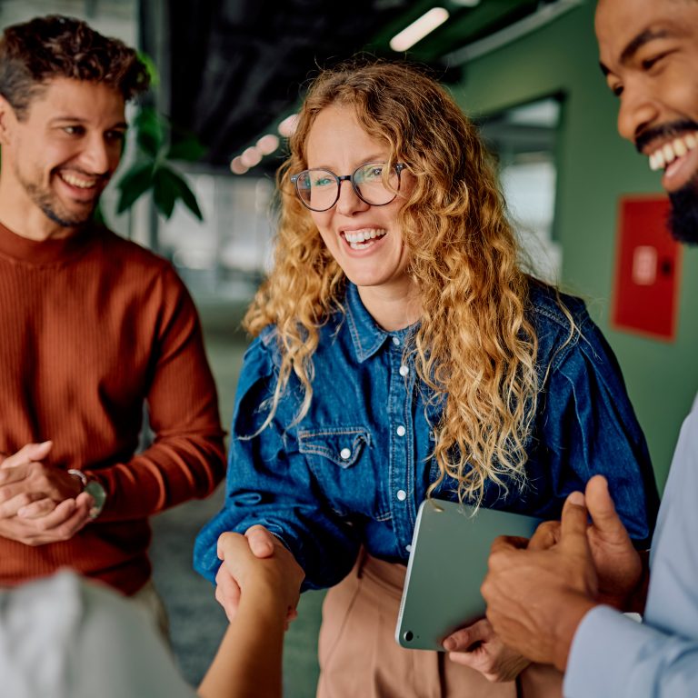 Business professionals shaking hands, celebrating collaboration and building a strong partnership in a modern office meeting